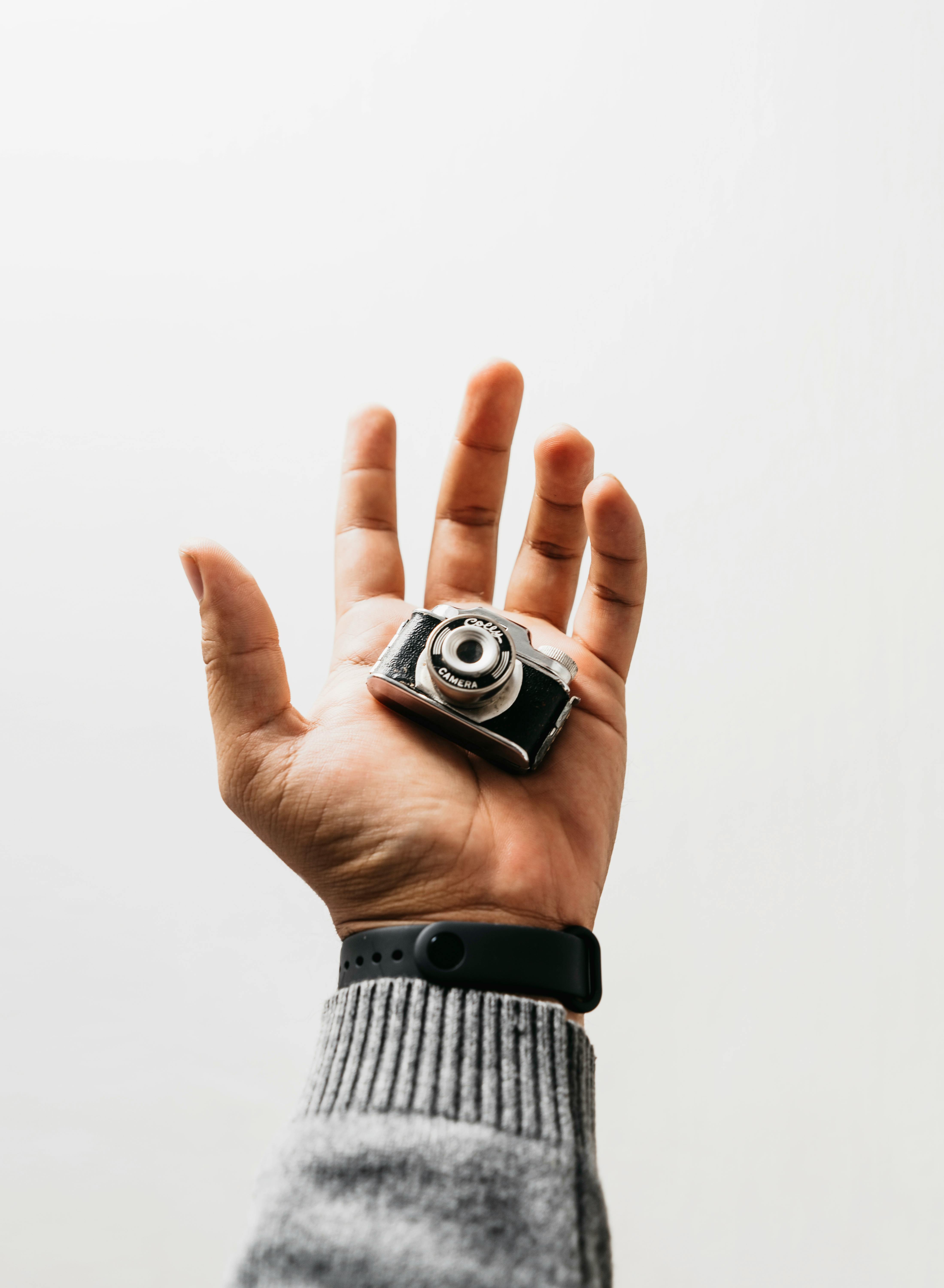 Minimalist image featuring a hand holding a miniature camera, perfect for creative concepts.