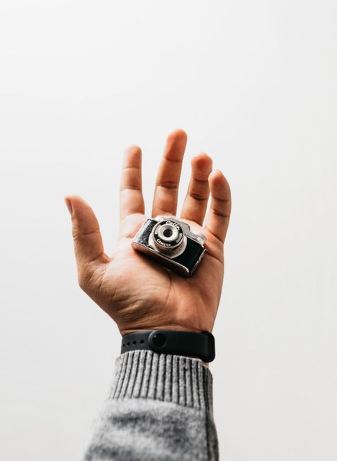 Minimalist image featuring a hand holding a miniature camera, perfect for creative concepts.