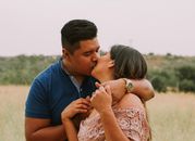 Latin American husband and wife kissing in field