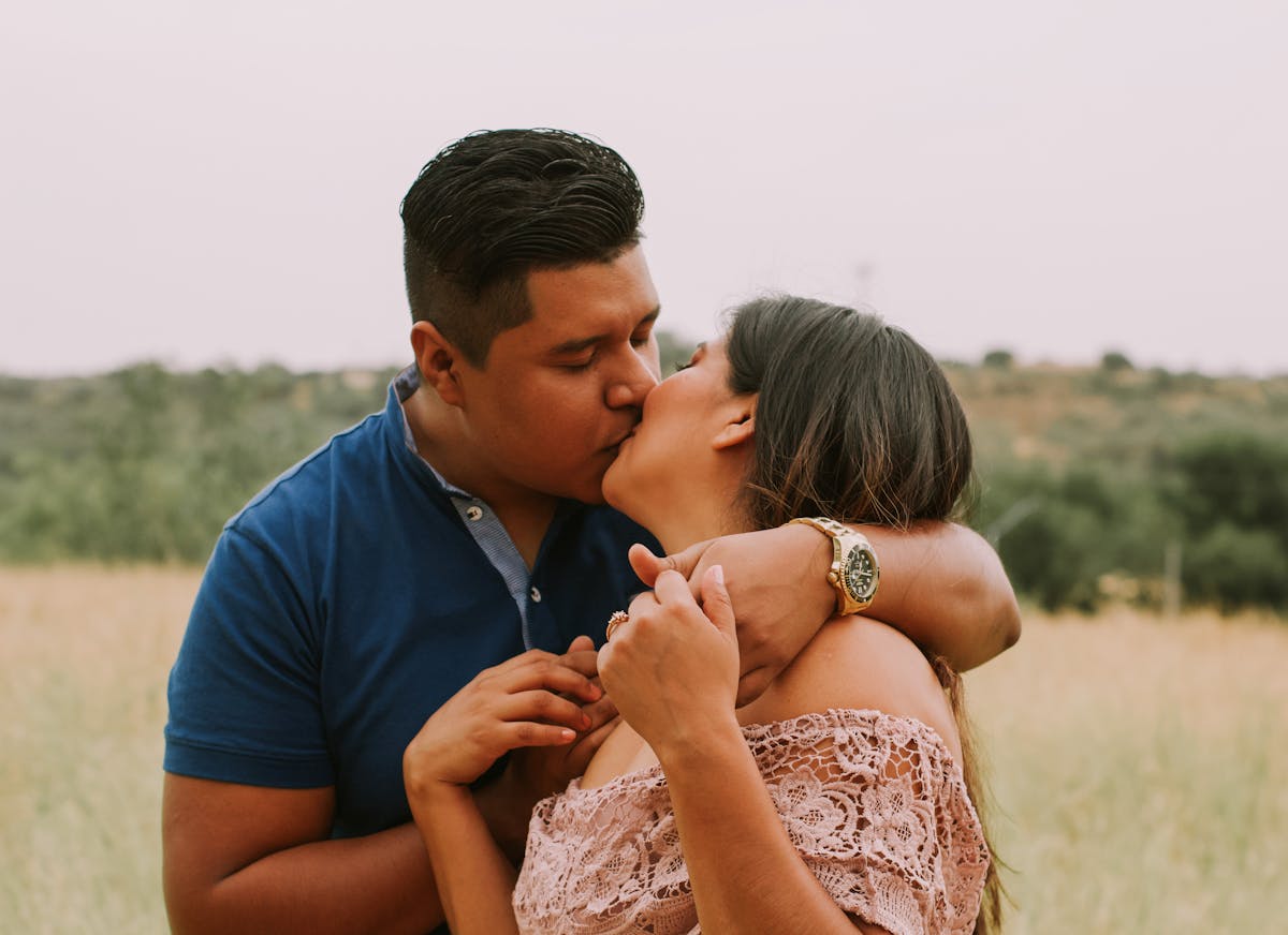 Latin American husband and wife kissing in field