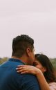Faceless boyfriend with stylish hairdo hugging unrecognizable girlfriend with long hair while putting hand with engagement ring on shoulder