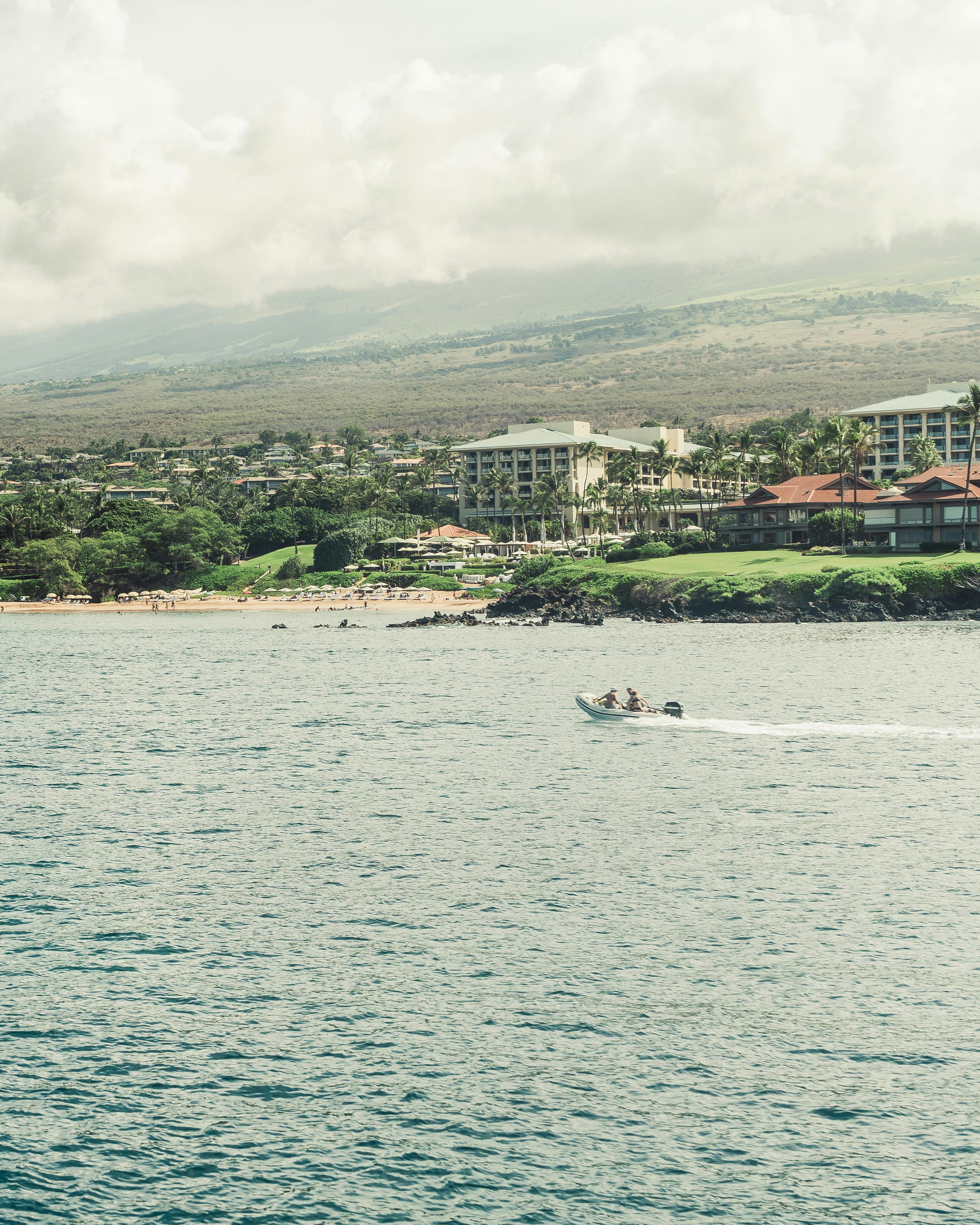 Prescription Goggle Inserts - A serene ocean scene with a boat near the coast of Maui, Hawaii, under a cloudy sky.