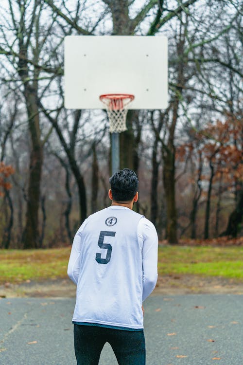 A Back View of a Man Facing the Basketball Ring