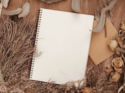 Free Notebook Beside Dried Leaves Stock Photo