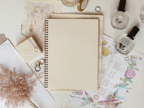 Notebook Beside Bottles and Jewelries