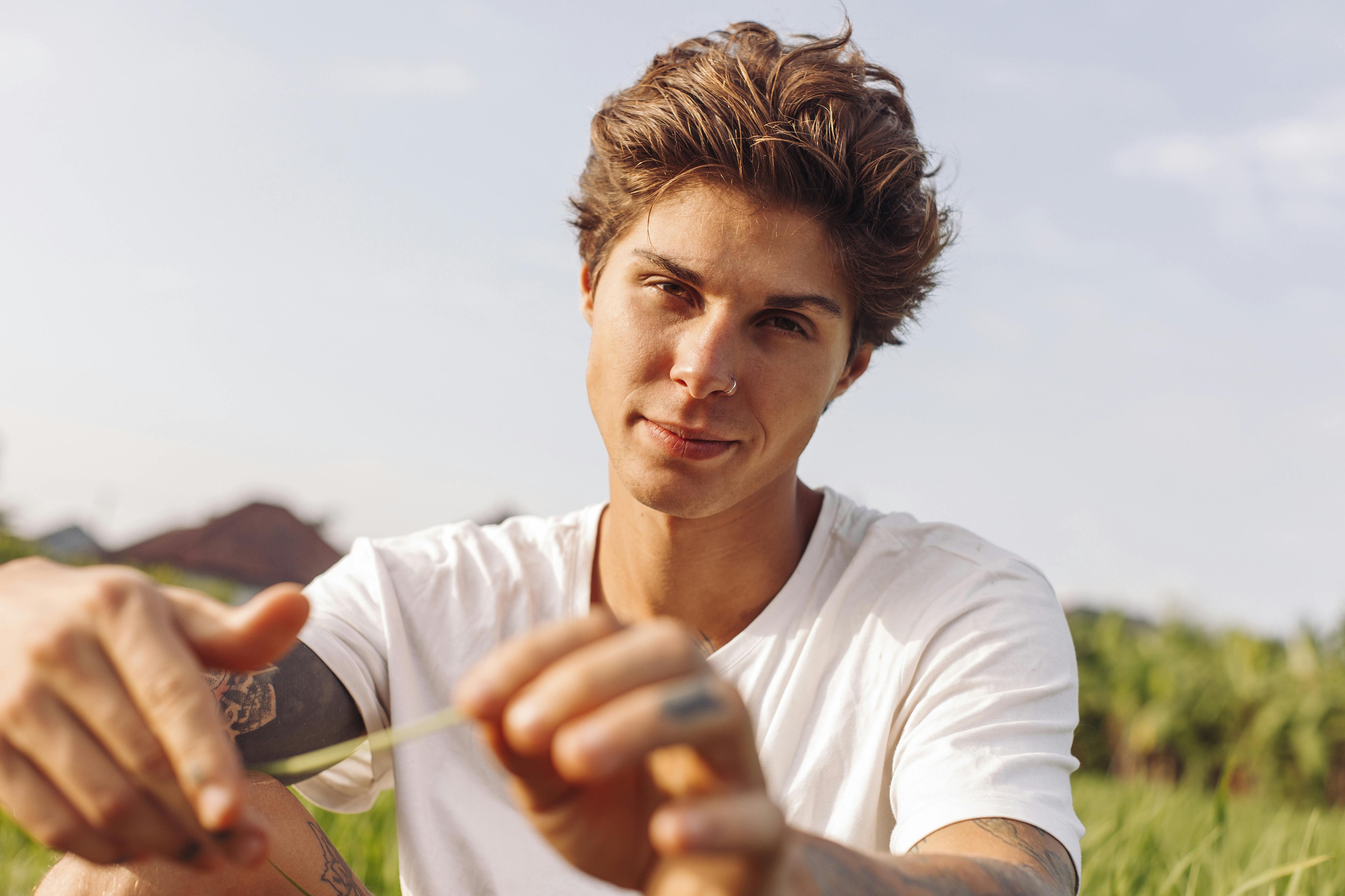 一位年轻人在大自然中享受阳光明媚的一天，他的肖像上有纹身