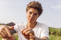 一位年轻人在大自然中享受阳光明媚的一天，他的肖像上有纹身