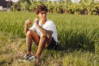 夏日阳光明媚，纹身男子坐在草地上享受休闲时光