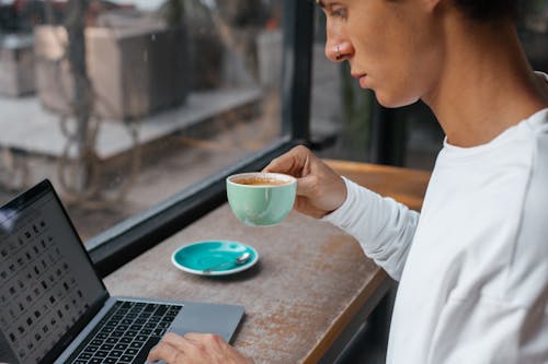 Free Man Drinking Coffee while Using Laptop Stock Photo