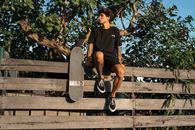 Teenage Boy Sitting on Wooden Fence with Skateboard