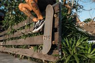 Person in Black and White Nike Sneakers Sitting on Brown Wooden Bench