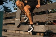 Man in Black and White Nike Sneakers Sitting on Brown Wooden Bench