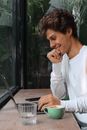Yong Man Using Laptop and Smiling in a Cafe