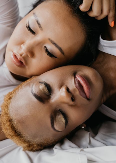 A close-up image of two diverse women with closed eyes, showcasing peaceful intimacy.
