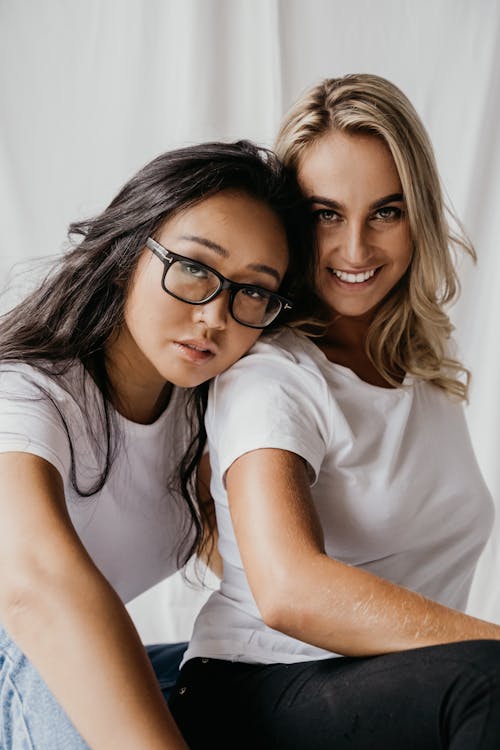 Woman in White T-shirt and Black Framed Eyeglasses Leaning on Woman's Shoulder