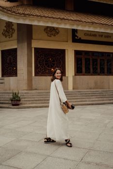 一位身着白色礼服的女人在寺庙外的户外微笑着