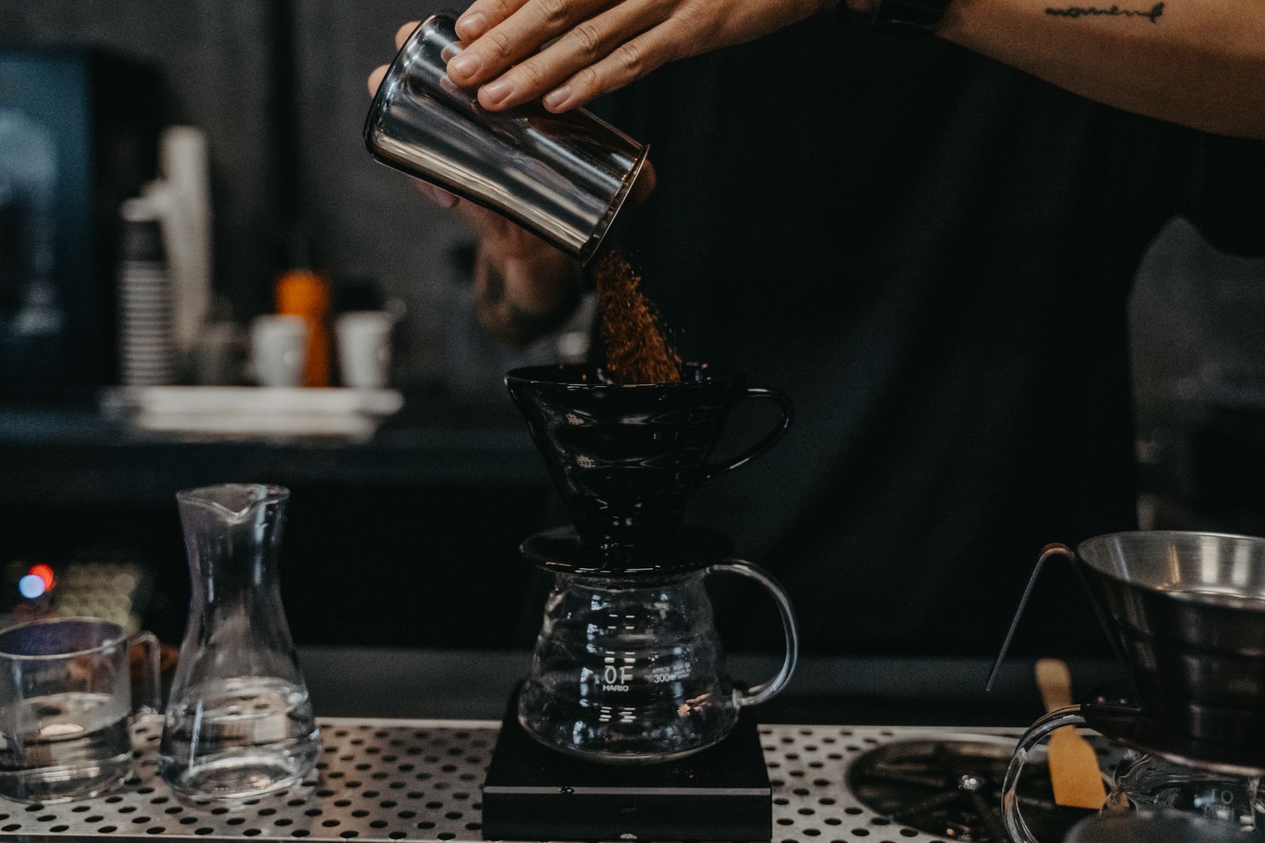Hand pouring hot water over ground coffee in a pour-over dripper