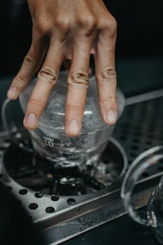 A hand pressing down on a coffee brewing tool in a modern kitchen environment.