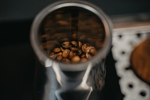 Detailed view of roasted coffee beans inside a metal filter with selective focus.