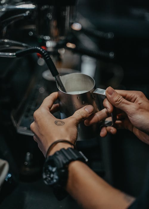Free A Person Holding Stainless Mug while Steaming Milk Stock Photo