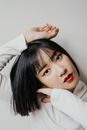 一位年轻的亚洲女性在室内摆出创意姿势，她画着引人注目的红唇和眼线，时尚肖像感十足