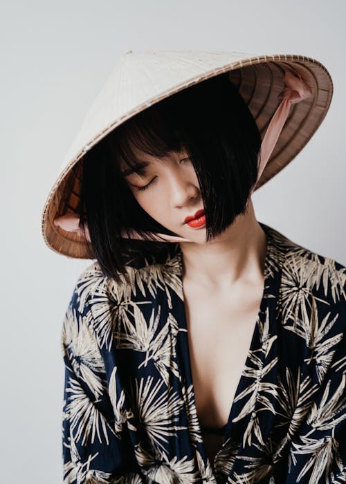 Woman in White and Black Floral Long Sleeve Shirt Wearing Brown Sun Hat