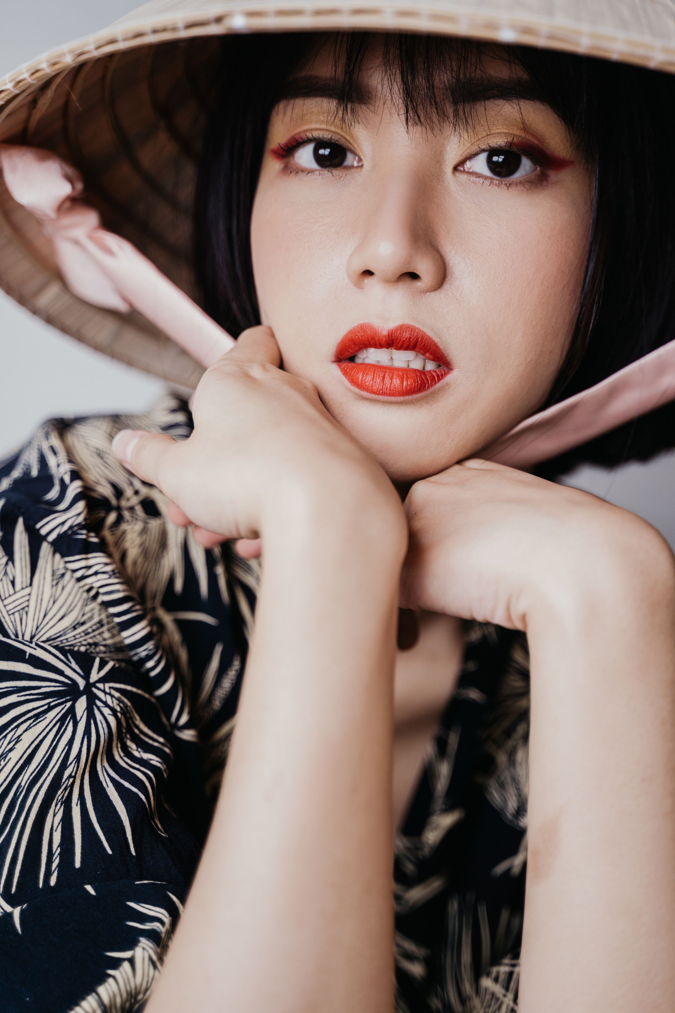Close-up portrait of a woman wearing a Vietnamese conical hat with a thoughtful expression.