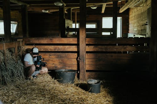 Man in Black Jacket Sitting on Brown Hay