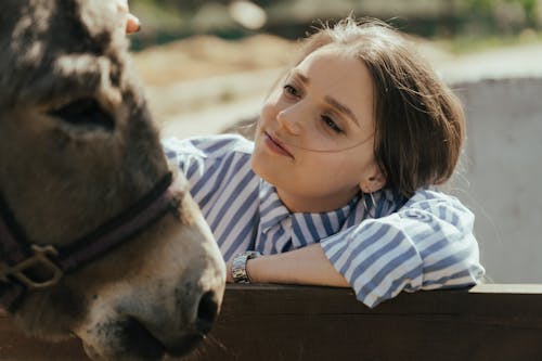 Girl in White and Black Striped Shirt Beside Brown Horse