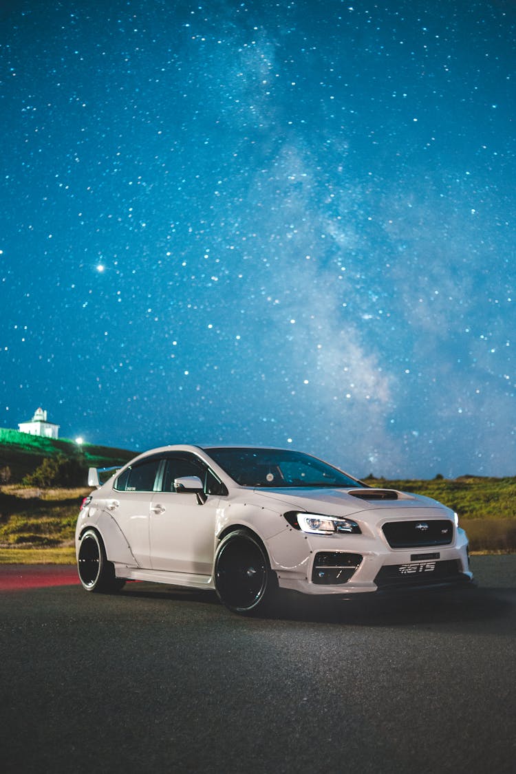 White Sports Car With Glowing Headlights Against Starry Sky