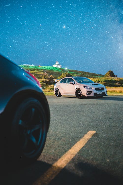 Modern sports cars parked on road in evening