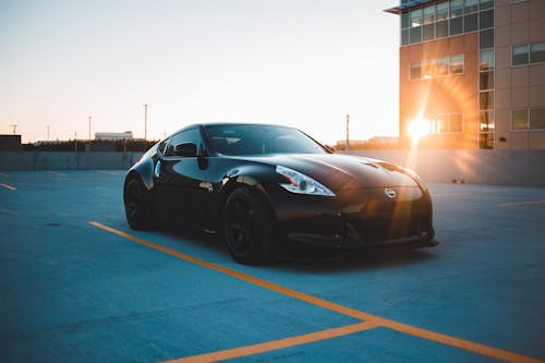 Stylish black car on parking area at sunset