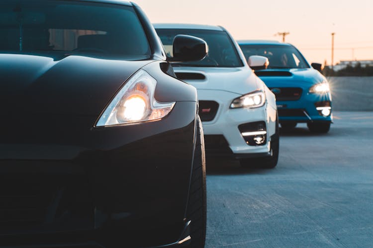 Headlights Of Cars Parked In Row In Evening