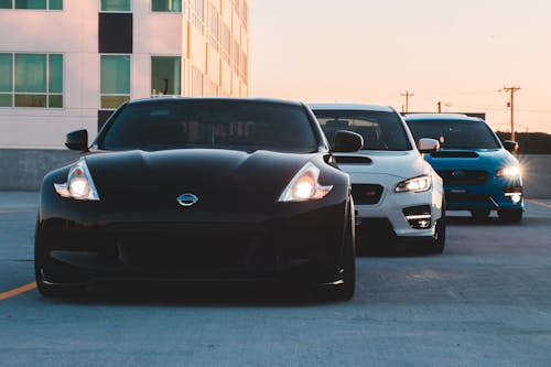 Modern expensive cars of different colors parked in line outside contemporary building in early evening