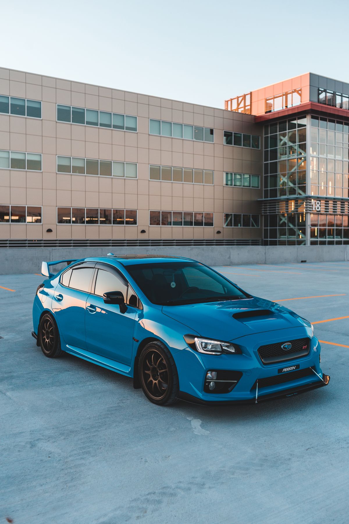 Exterior of coupe blue car parked on asphalt parking outside modern building in early evening Illustrative editorial photograph.