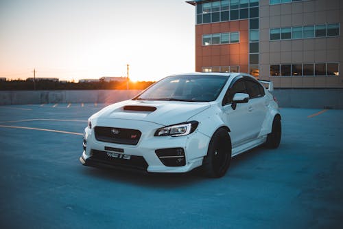 Powerful white car on industrial building parking at sunset