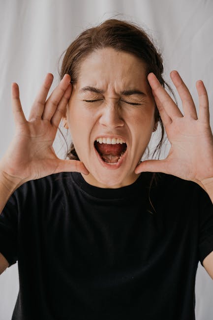 Portrait of a woman expressing emotion with her eyes closed and mouth open, conveying a loud shout.