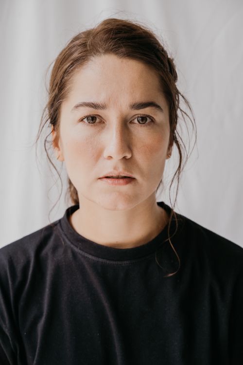 Free Close-up portrait of a serious woman in a black shirt against a neutral background. Stock Photo