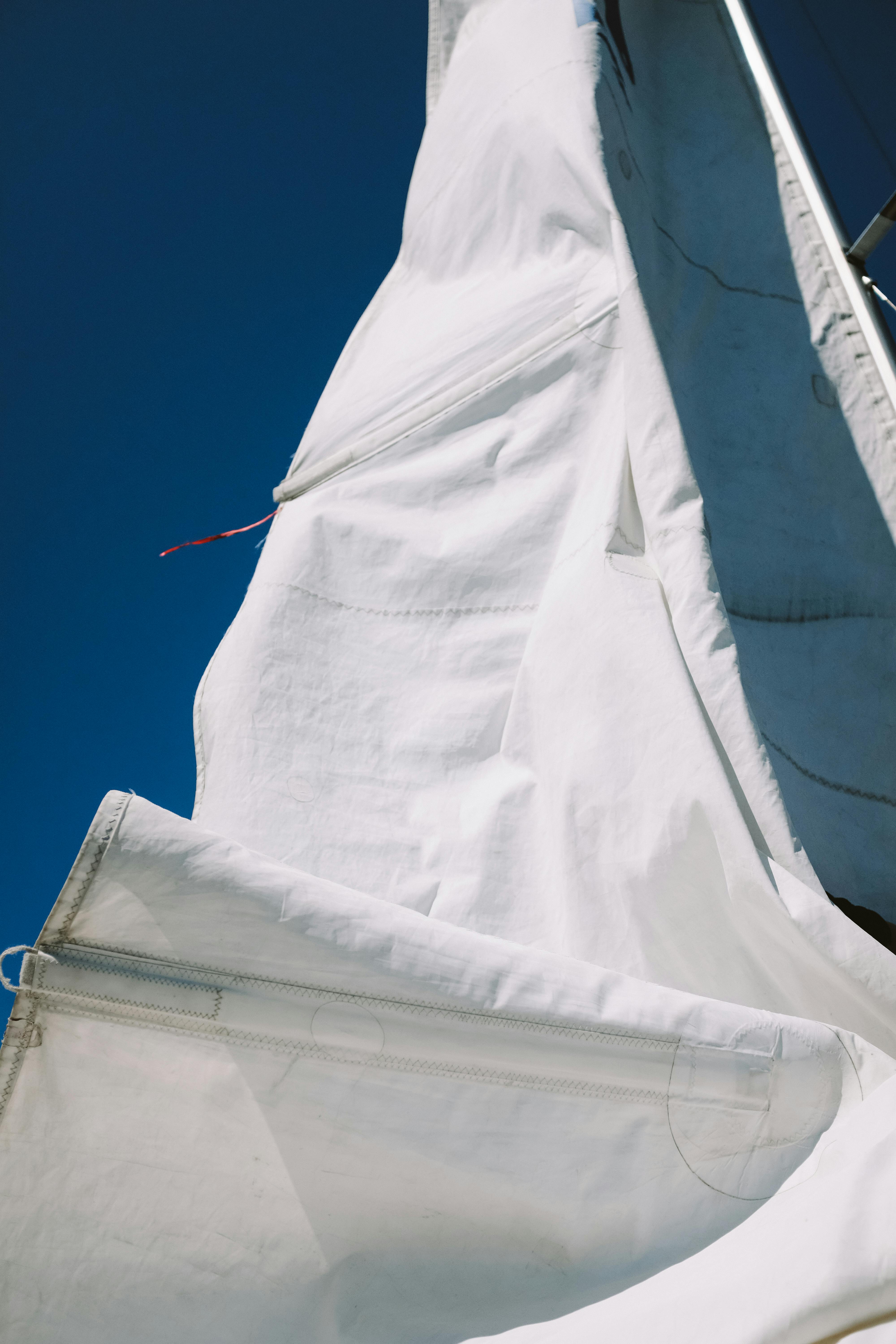 Detailed view of a white sail on a yacht set against a vibrant blue sky, capturing the essence of sailing.
