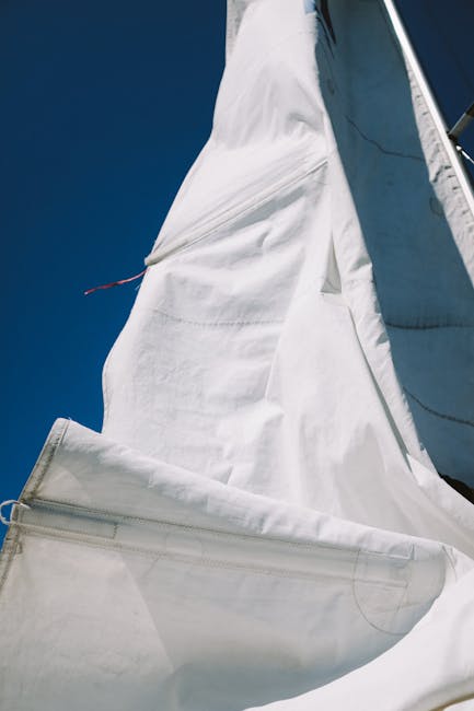 Detailed view of a white sail on a yacht set against a vibrant blue sky, capturing the essence of sailing.