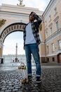 Man in Black and White Plaid Dress Shirt and Blue Denim Jeans Standing on Gray Concrete