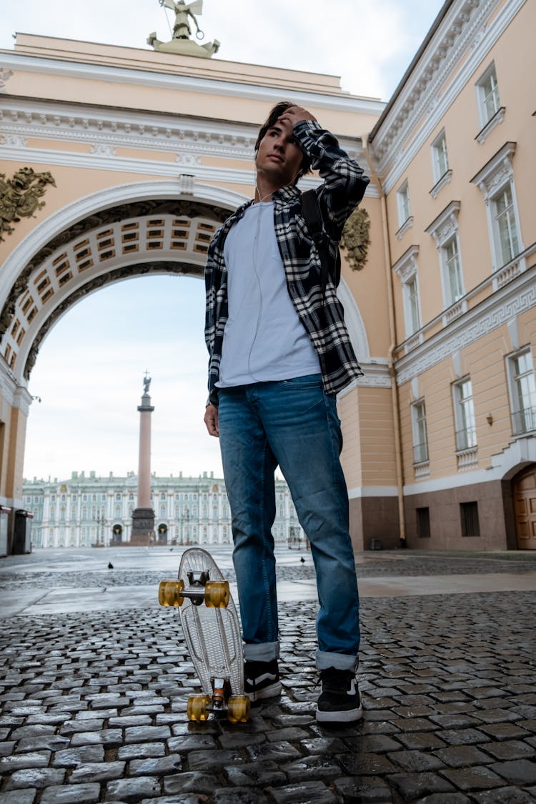 Man In Black And White Plaid Dress Shirt And Blue Denim Jeans Standing On Gray Concrete