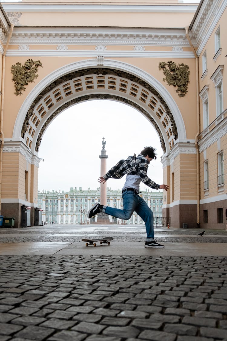 Man In Black Jacket And Blue Denim Jeans Jumping On Brown Concrete Floor