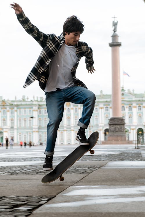 Man in Black and White Plaid Dress Shirt and Blue Denim Jeans Sitting on Black Skateboard