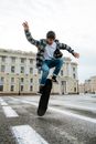Man in Blue and White Plaid Dress Shirt and Blue Denim Jeans Jumping on Gray Concrete