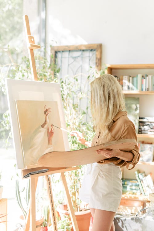 Woman Holding a Brush Painting on a Canvass