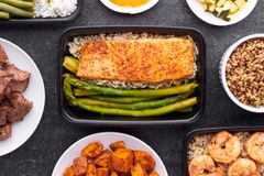 Flat lay of meal prep containers featuring salmon, asparagus, shrimp, and sweet potatoes.