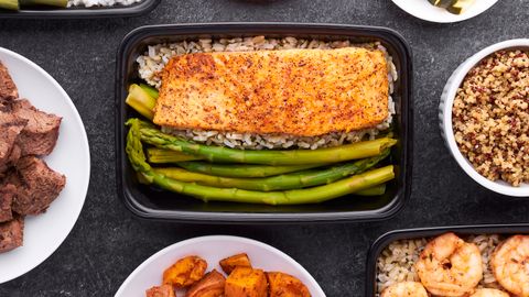 Flat lay of meal prep containers featuring salmon, asparagus, shrimp, and sweet potatoes.