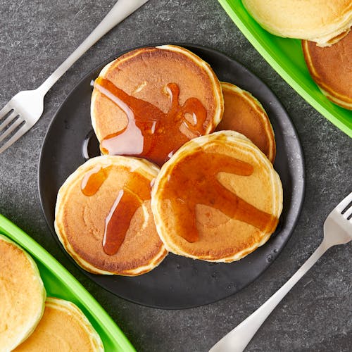 A Pancakes with Syrup on a Black Plate