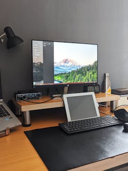 Tidy home office with monitor, tablet, keyboard on wooden desk.